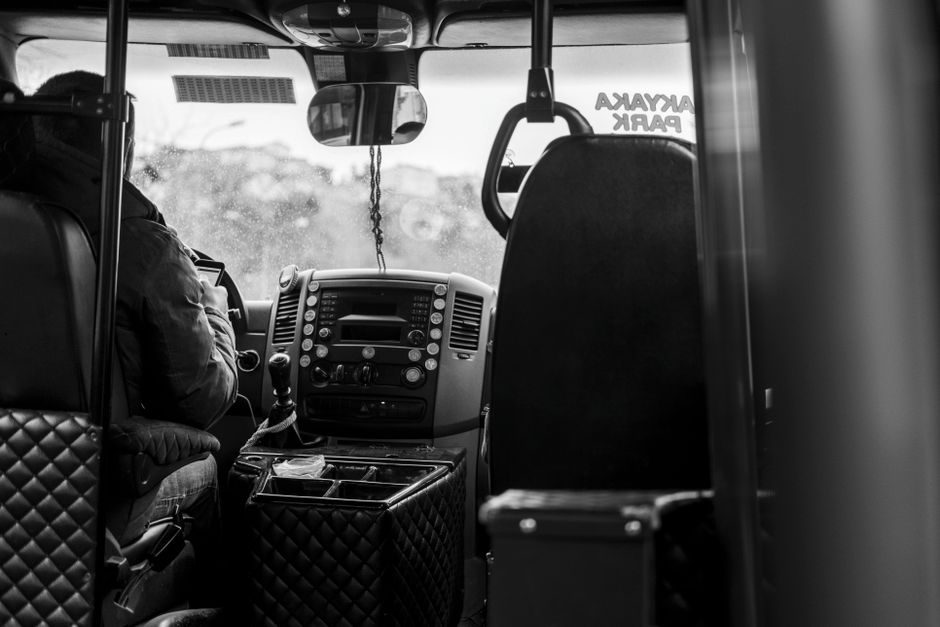 Een buschauffeur aan het werk in een stadsomgeving, met passagiers die instappen en uitstappen bij een bushalte.